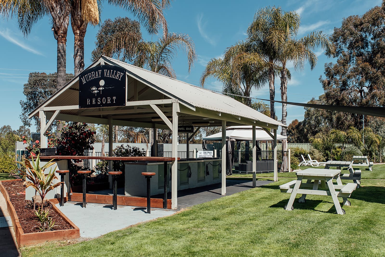 Covered outdoor bar and BBQ pavilion with picnic tables on the resort lawn