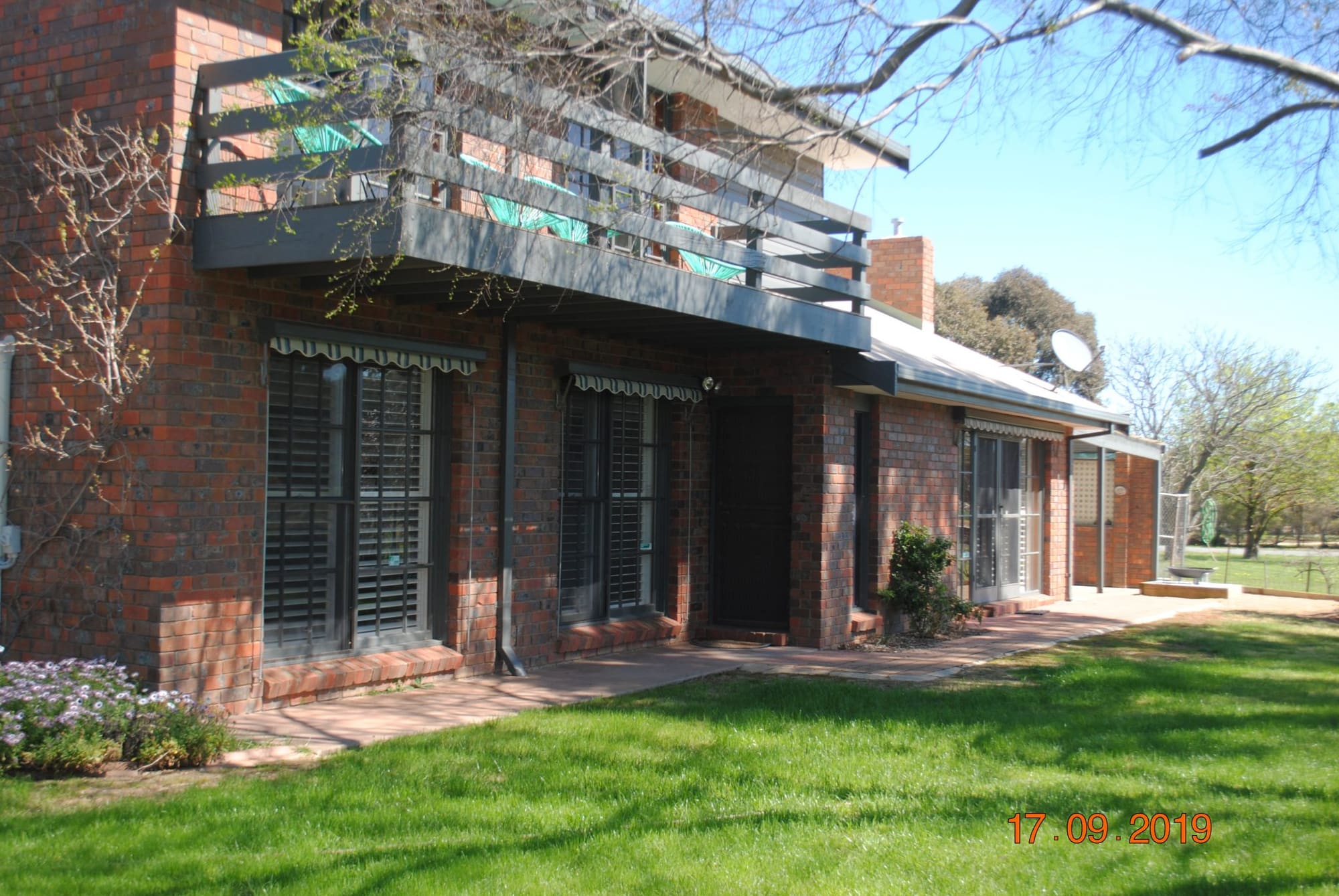 Two-storey brick accommodation block with a balcony, facing a grassed lawn