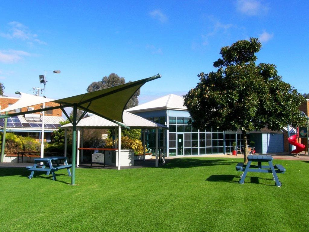 Shade sail and picnic tables on the resort lawn