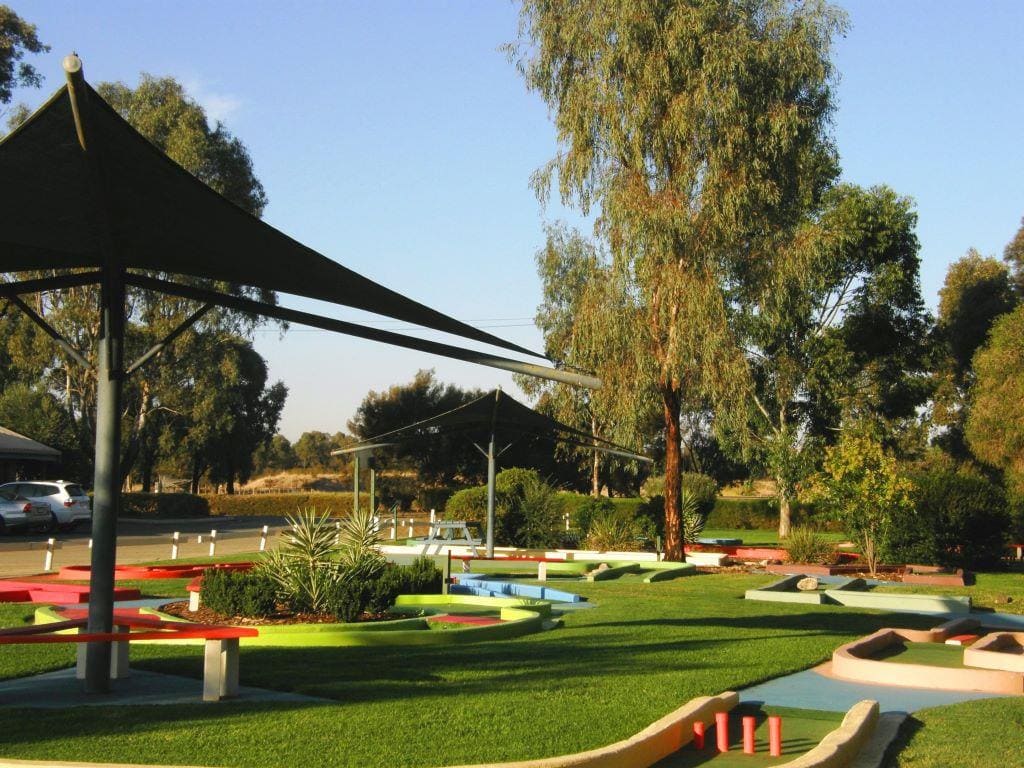 Mini-golf course beneath gum trees and a shade sail