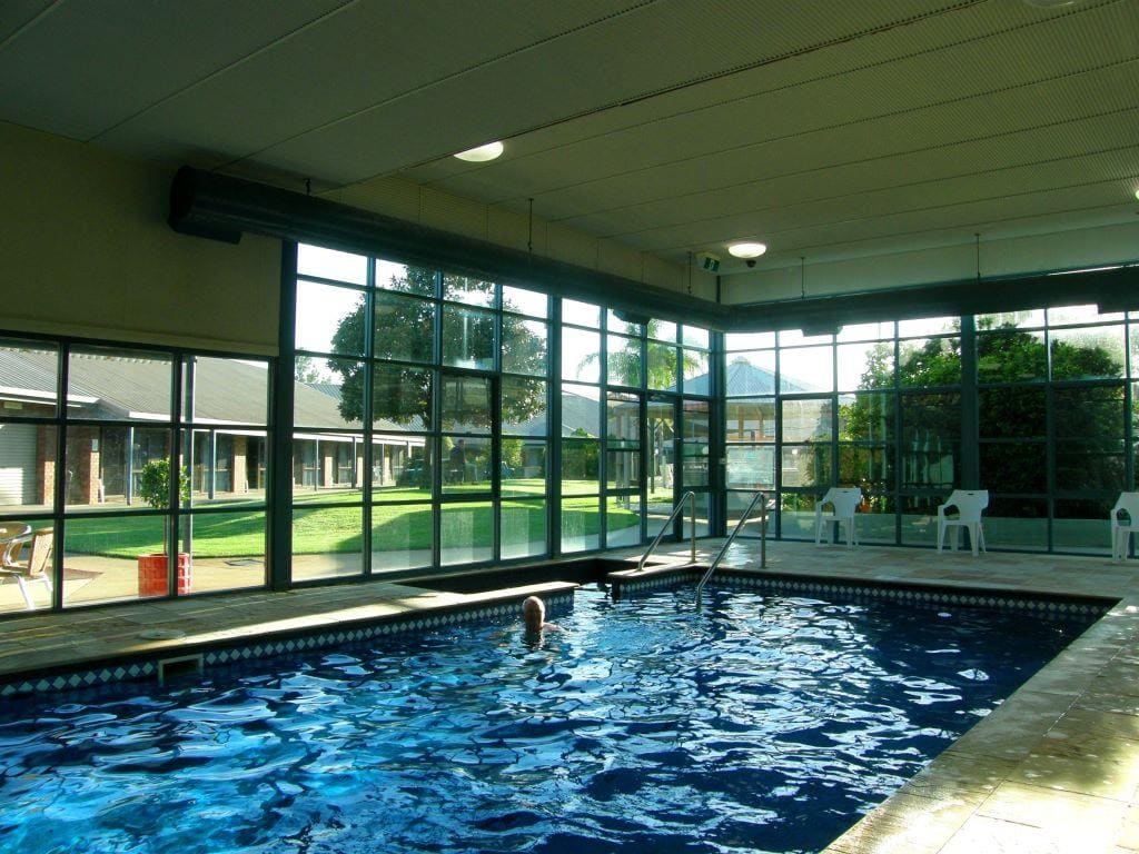 Indoor pool with glass walls looking out to the garden