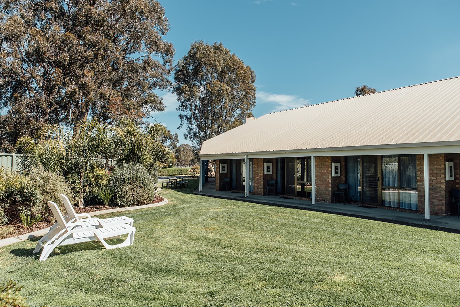 Motel wing with a manicured lawn and sun loungers in front