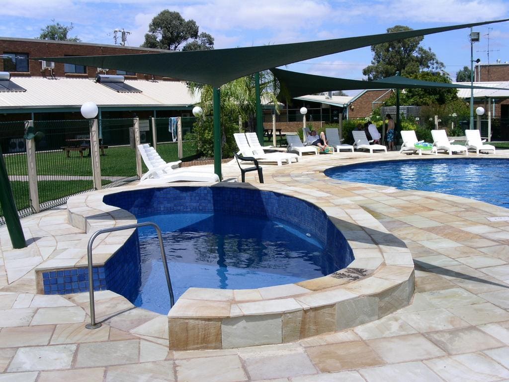 Spa pool in the foreground with the outdoor pool and sun loungers beyond